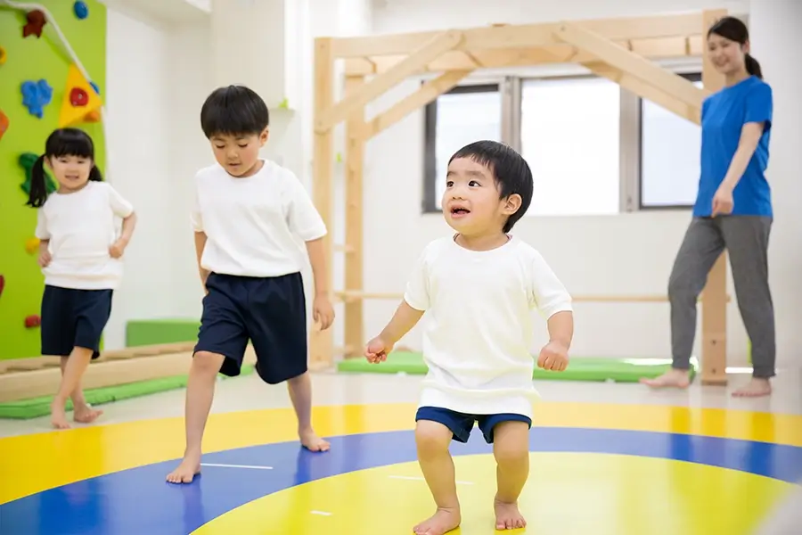 部屋内で運動遊びをする子供 写真